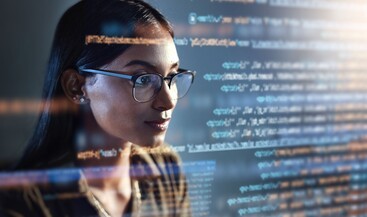 Woman with glasses looking at lines of code