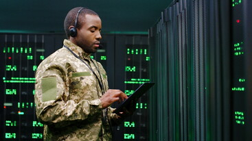 man in army uniform working on a tablet within a security centre